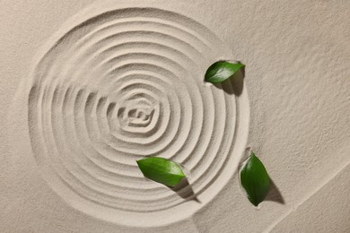 Photo of Beautiful spiral and leaves on sand, top view. Zen garden