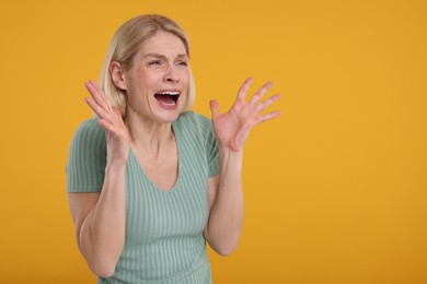 Portrait of surprised woman on yellow background, space for text