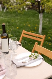 Photo of Stylish table setting with beautiful spring flowers, wine, plates and glasses in garden