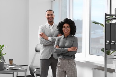 Young smiling colleagues near window in modern office