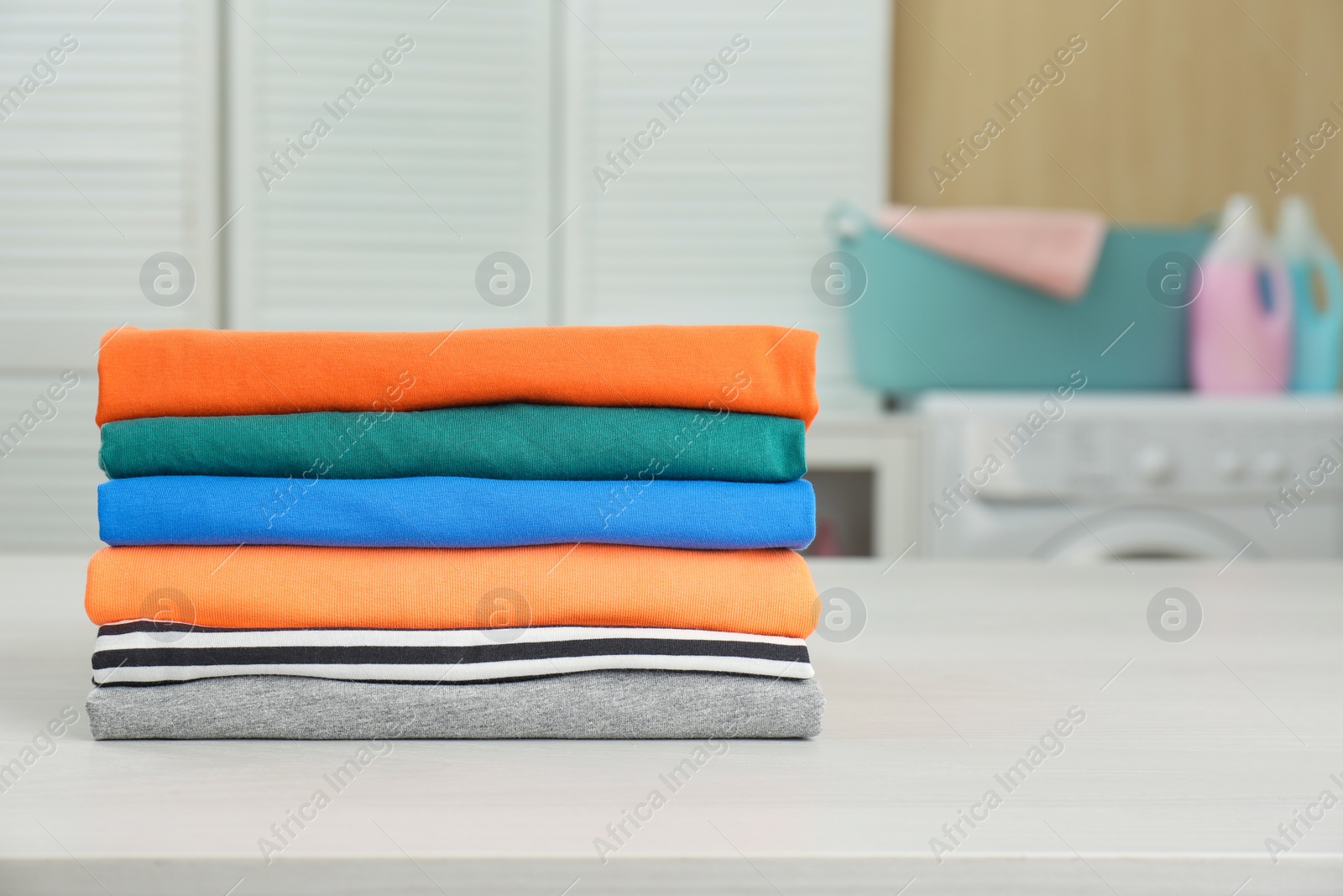 Photo of Fresh laundry on white wooden table in bathroom