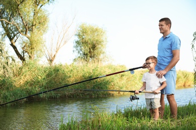 Dad and son fishing together on sunny day