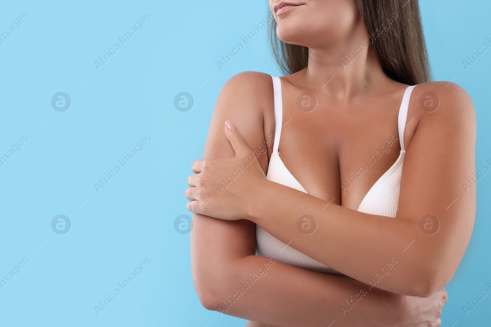 Photo of Woman with beautiful breast on light blue background, closeup. Space for text