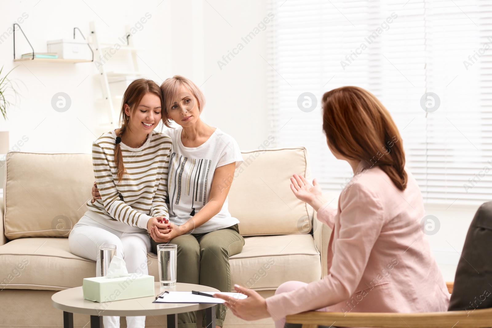 Photo of Psychotherapist working with teenage girl and her mother in office