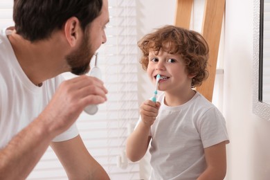 Photo of Father and his son brushing teeth together in bathroom
