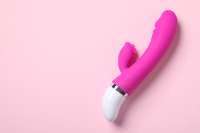 Photo of Vibrator on pink background, top view with space for text. Sex toy