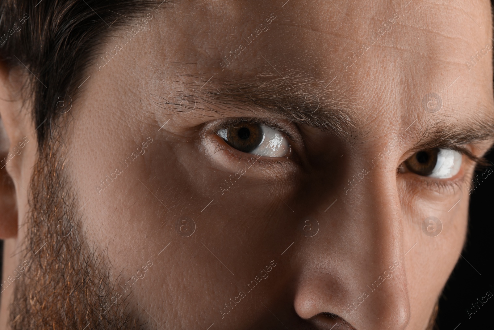 Photo of Evil eye. Man with scary eyes on black background, closeup