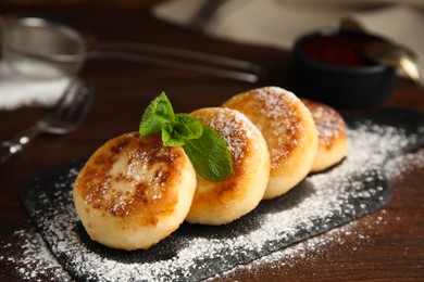 Delicious cottage cheese pancakes with mint and icing sugar on wooden table, closeup