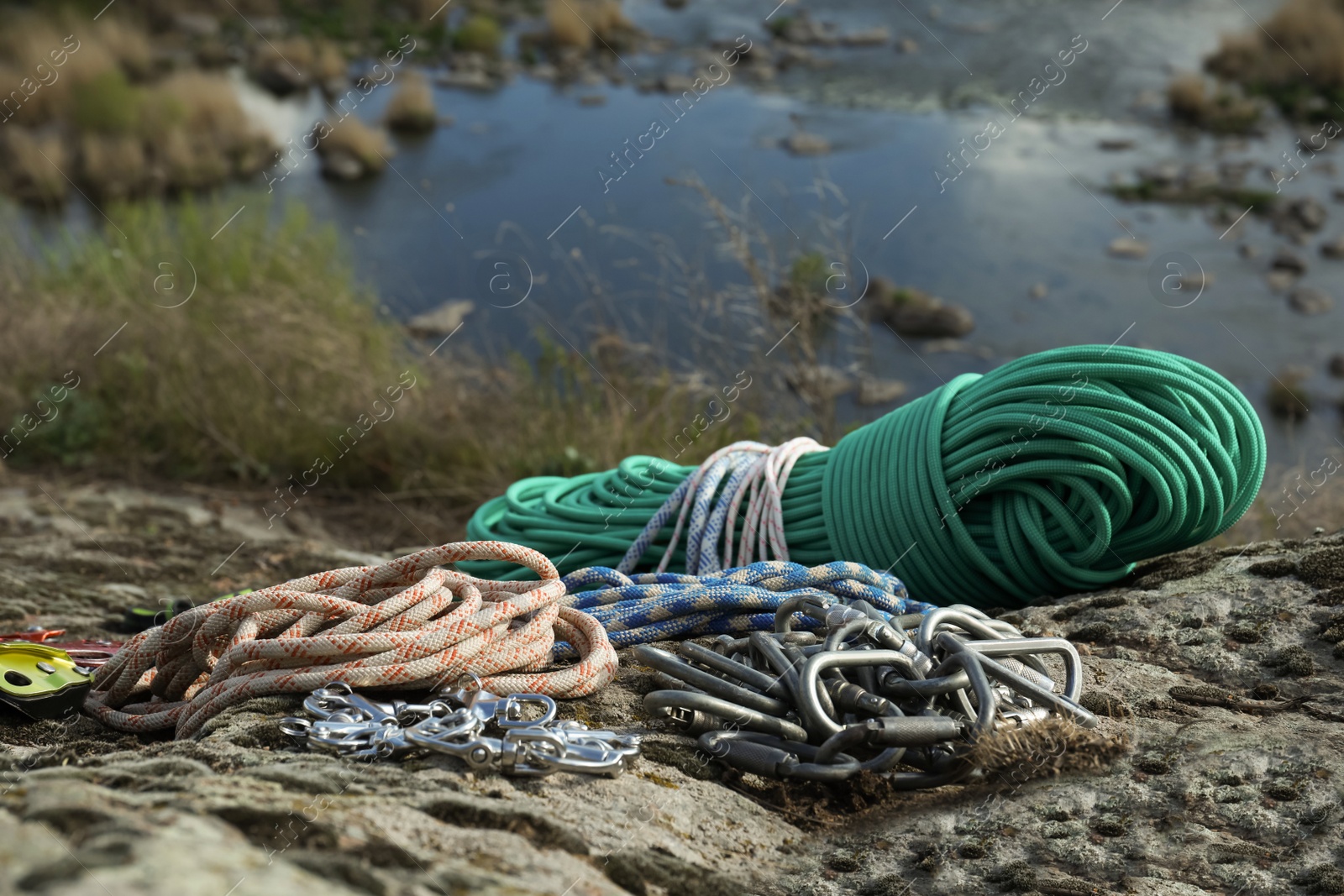 Photo of Different ropes and other climbing equipment on rock near river