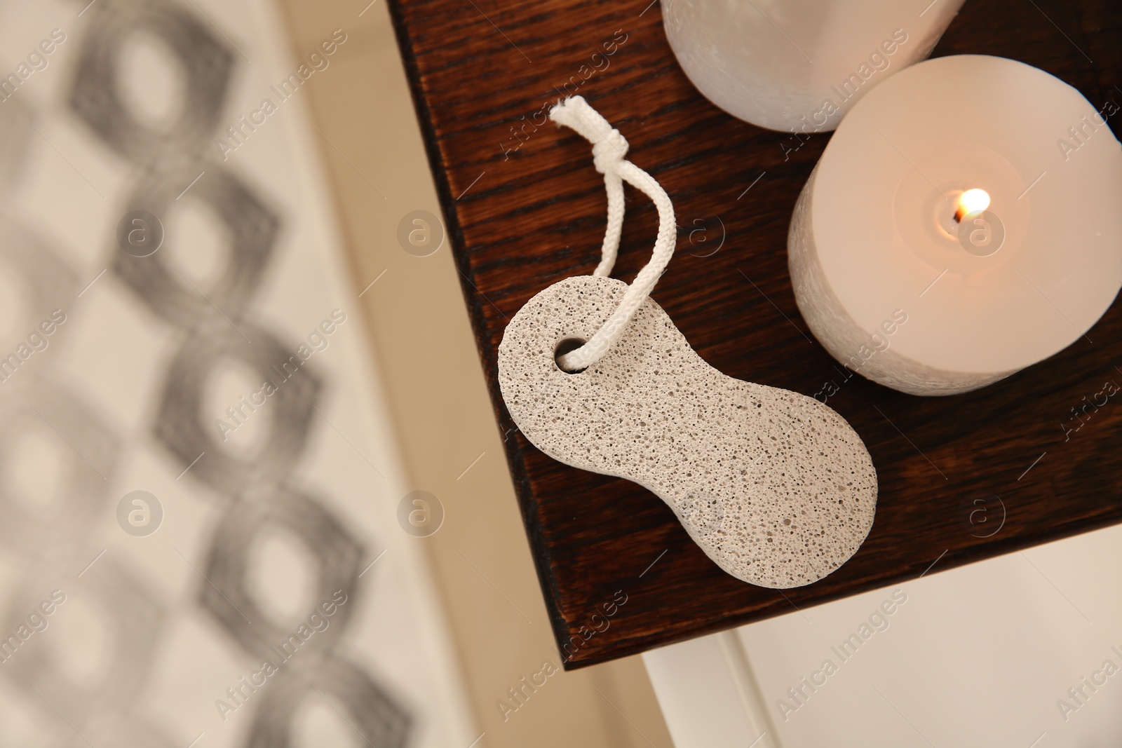 Photo of Pumice stone and burning candle on wooden caddy indoors, top view. Space for text