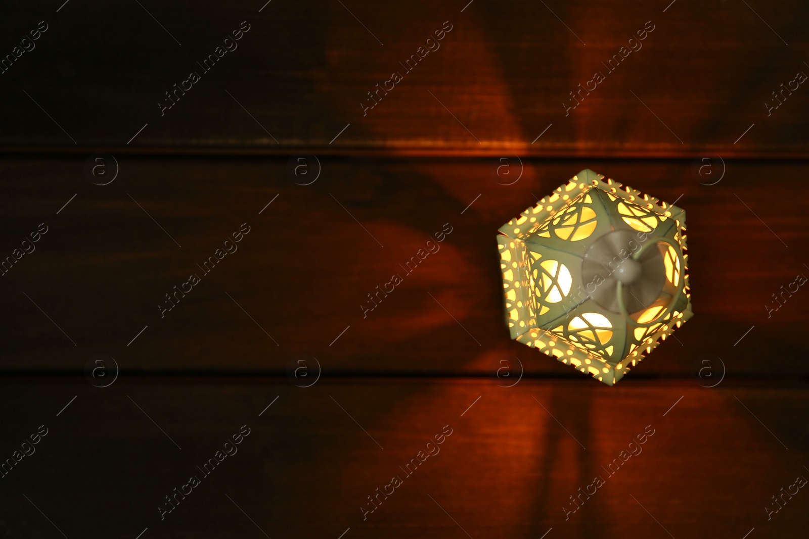 Photo of Decorative Arabic lantern on wooden table, top view. Space for text