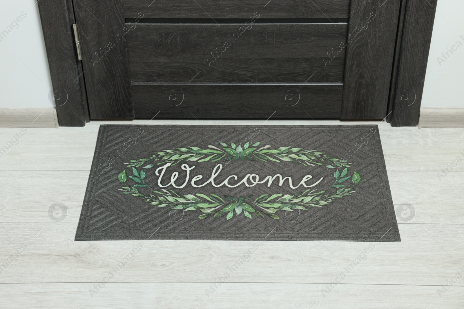 Photo of Doormat with word Welcome on white floor near entrance