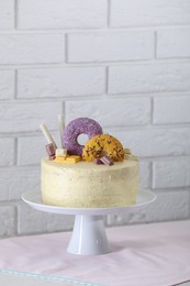 Photo of Delicious cake decorated with sweets on table near white brick wall, space for text