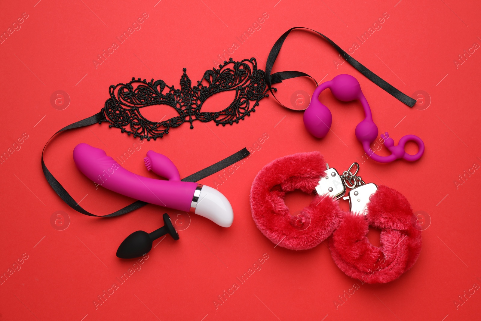 Photo of Sex toys and accessories on red background, flat lay