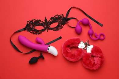 Sex toys and accessories on red background, flat lay