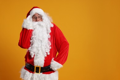 Photo of Merry Christmas. Surprised Santa Claus on orange background, space for text