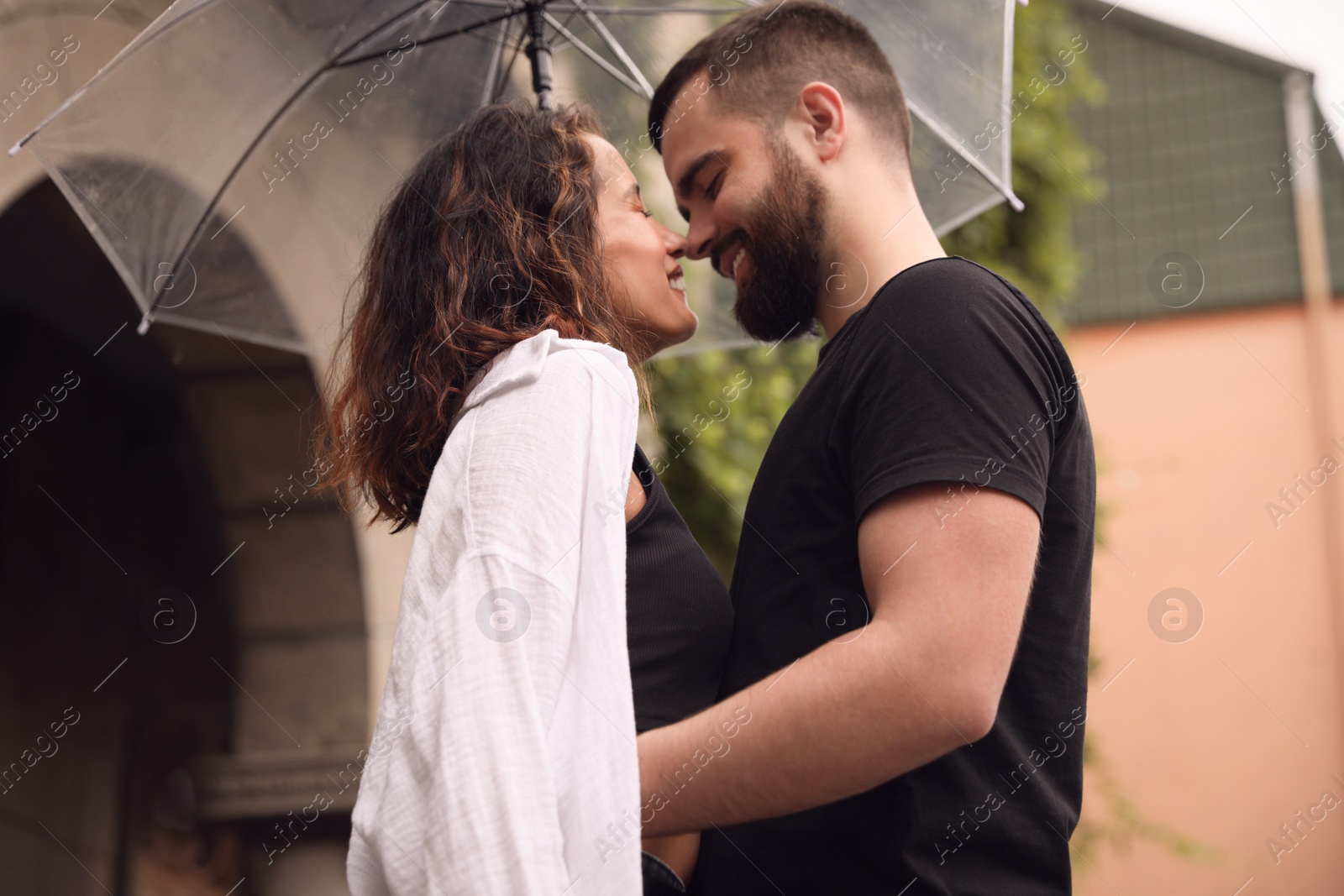 Photo of Young couple with umbrella enjoying time together under rain on city street