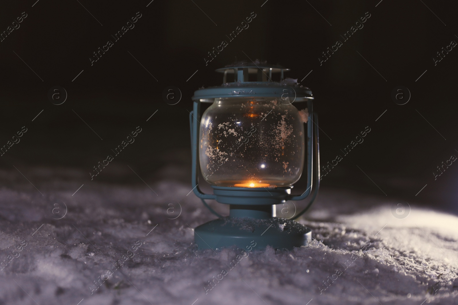 Photo of Lantern with burning candle on white snow outdoors. Space for text