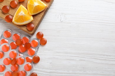 Photo of Many orange cough drops on white wooden table, flat lay. Space for text