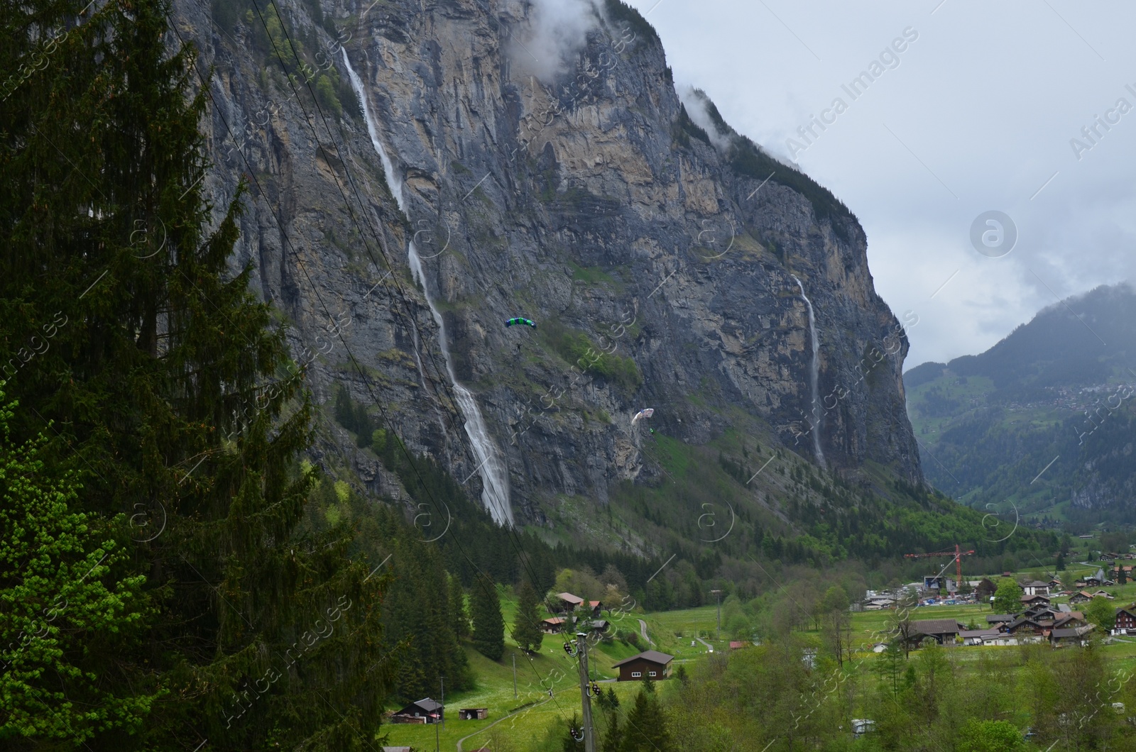 Photo of Picturesque view of high mountains and village on cloudy day