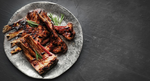 Plate with delicious grilled ribs and space for text on grey table, top view. Banner design