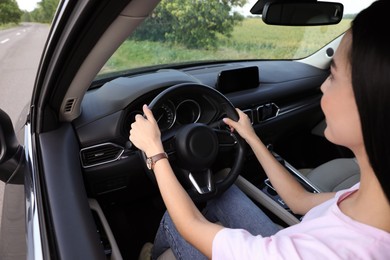Photo of Young woman driving her modern car, closeup