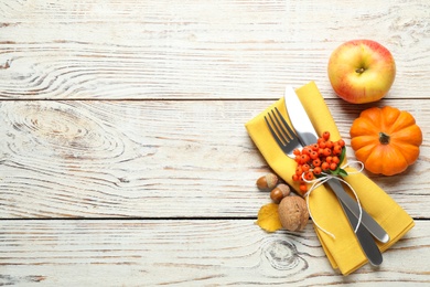 Photo of Top view of cutlery with napkin and autumn items on white wooden table, space for text. Thanksgiving Day
