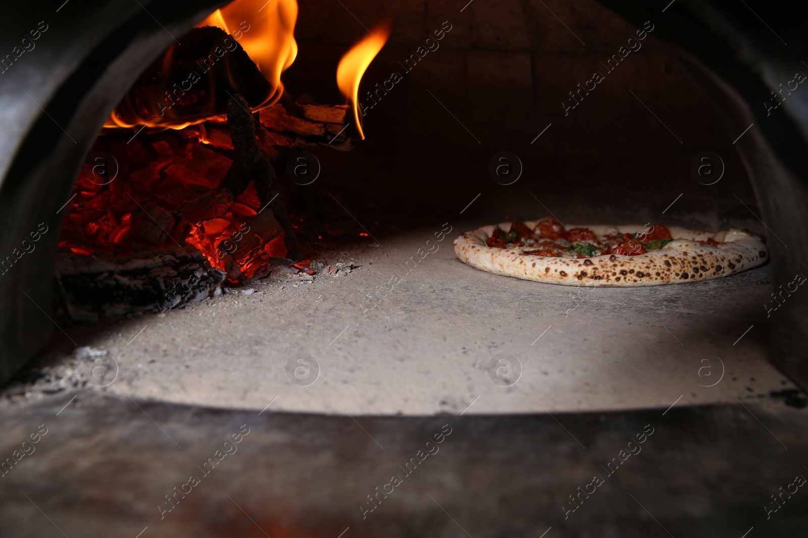 Photo of Burning firewood and tasty pizza in oven at restaurant kitchen