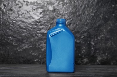 Photo of Motor oil in blue canister on black table near dark wall
