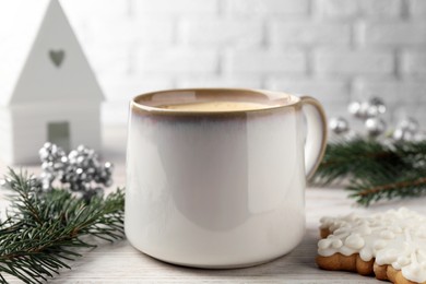 Photo of Cup of delicious eggnog, fir branch and cookie on wooden table, closeup