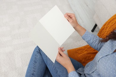 Photo of Young woman with greeting card on floor in living room, closeup