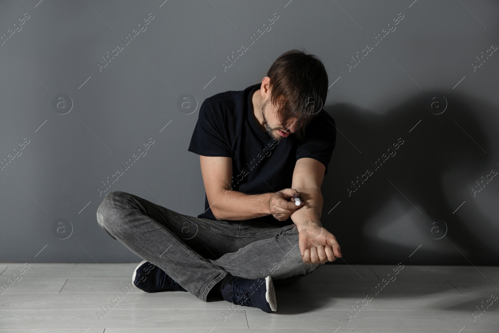 Photo of Male drug addict making injection near grey wall