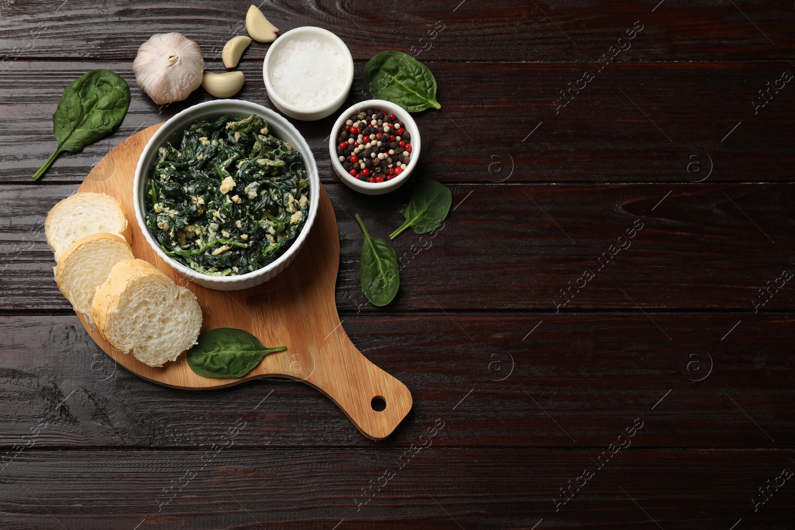 Photo of Tasty spinach dip with egg in bowl, spices and bread on wooden table, top view. Space for text