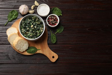 Photo of Tasty spinach dip with egg in bowl, spices and bread on wooden table, top view. Space for text