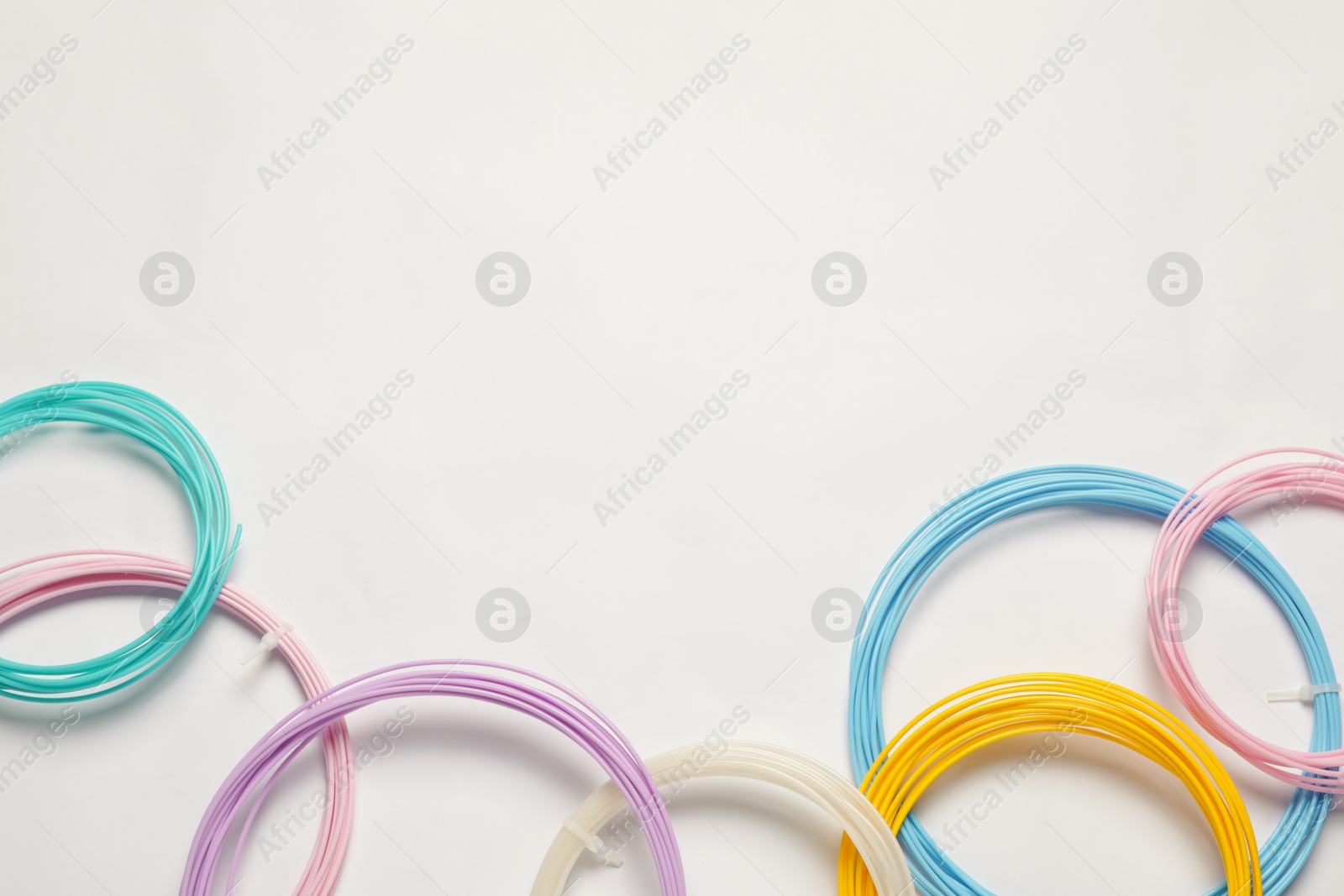 Photo of Colorful plastic filaments for 3D pen on white background, flat lay. Space for text