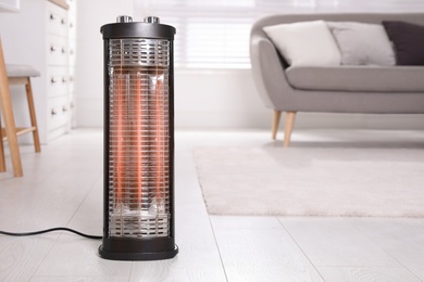 Photo of Modern electric heater on floor at home. Space for text