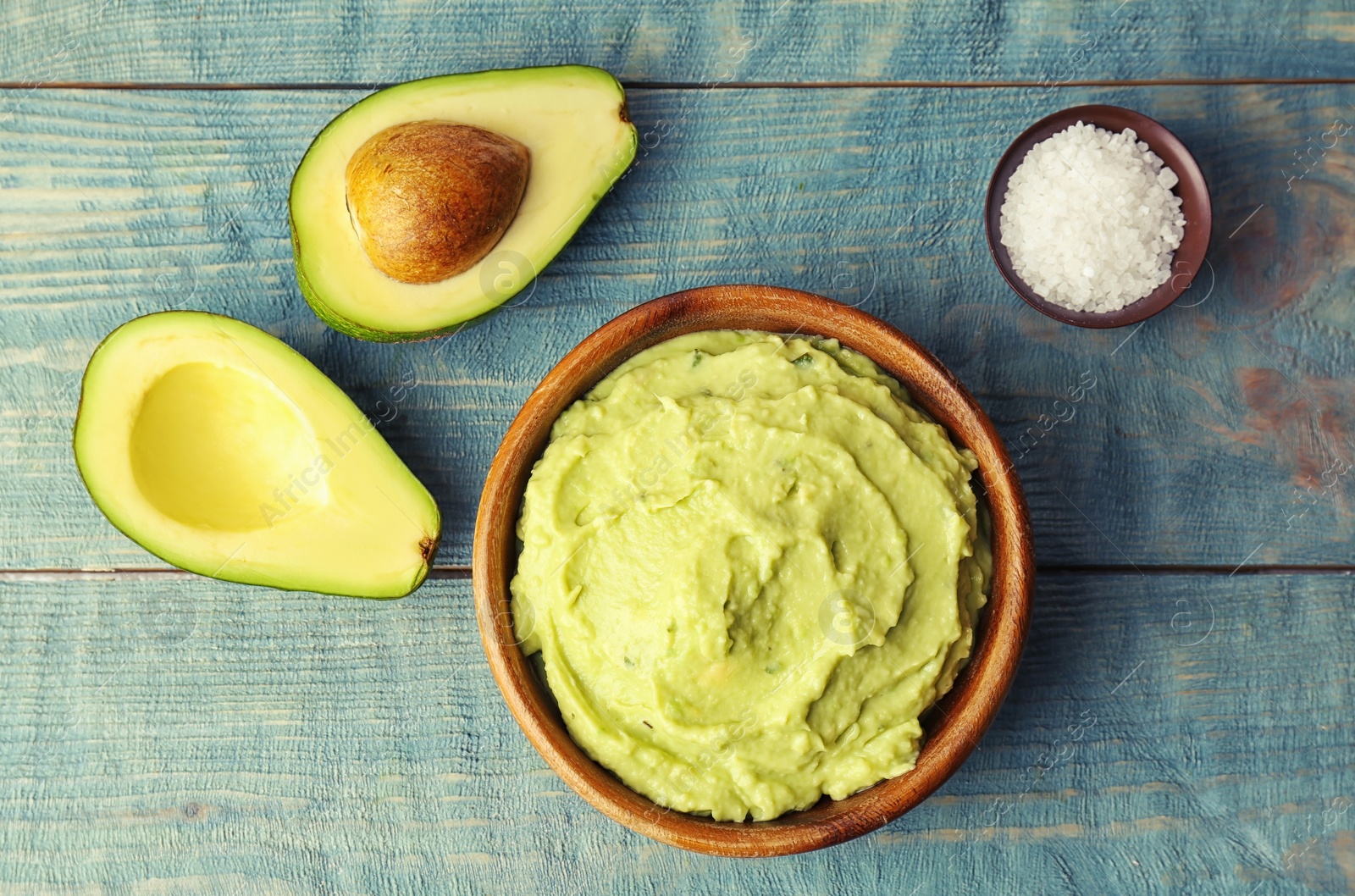 Photo of Flat lay composition with guacamole sauce, salt and ripe avocado on wooden background