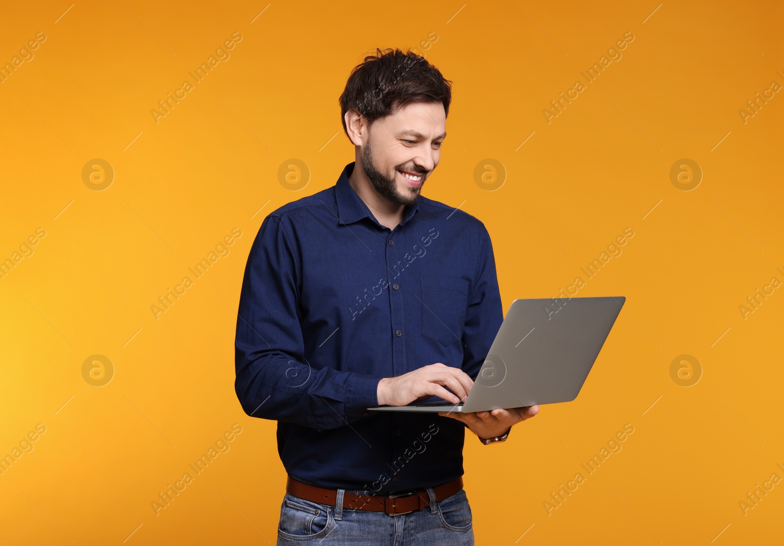 Photo of Happy man with laptop on yellow background