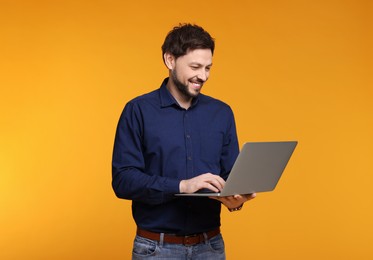 Happy man with laptop on yellow background