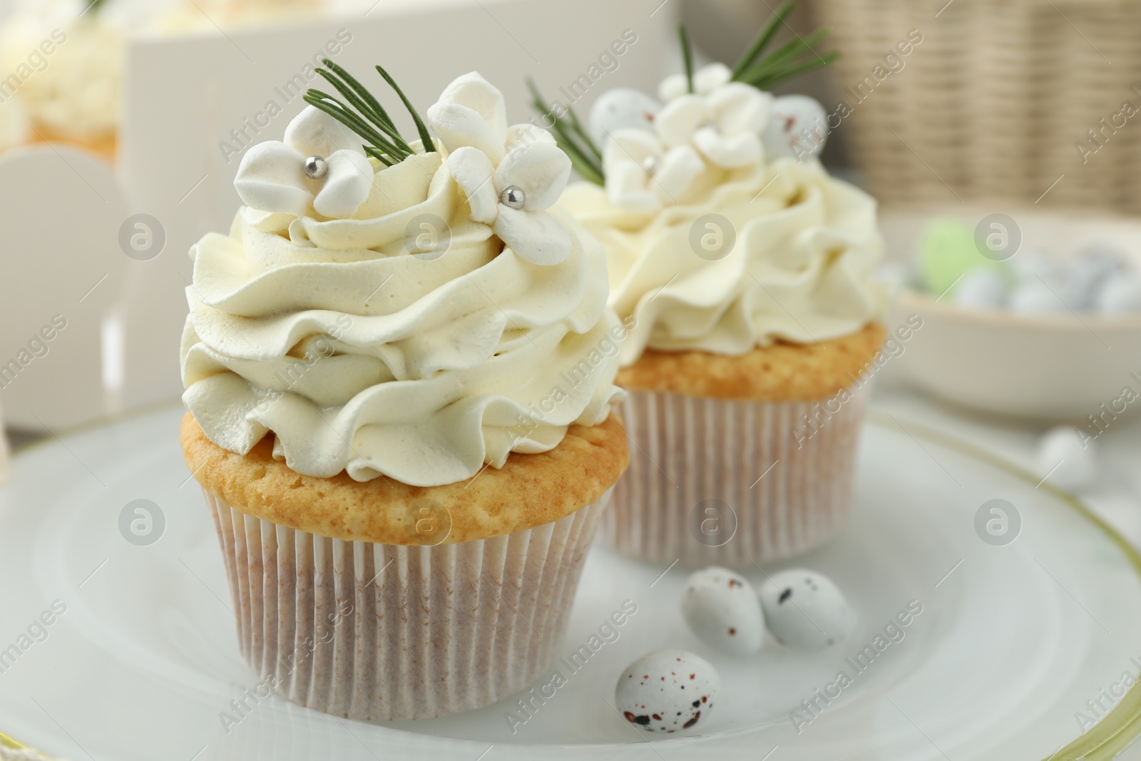 Photo of Tasty Easter cupcakes with vanilla cream on table, closeup