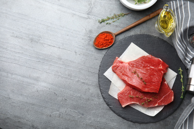 Photo of Flat lay composition with fresh beef cut on grey table. Space for text