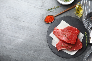 Flat lay composition with fresh beef cut on grey table. Space for text