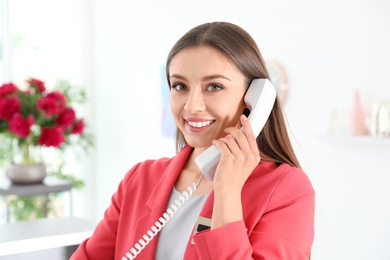Photo of Beauty salon receptionist talking on phone at workplace