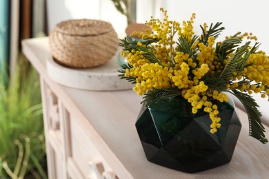 Photo of Beautiful mimosa flowers on chest of drawers indoors, space for text