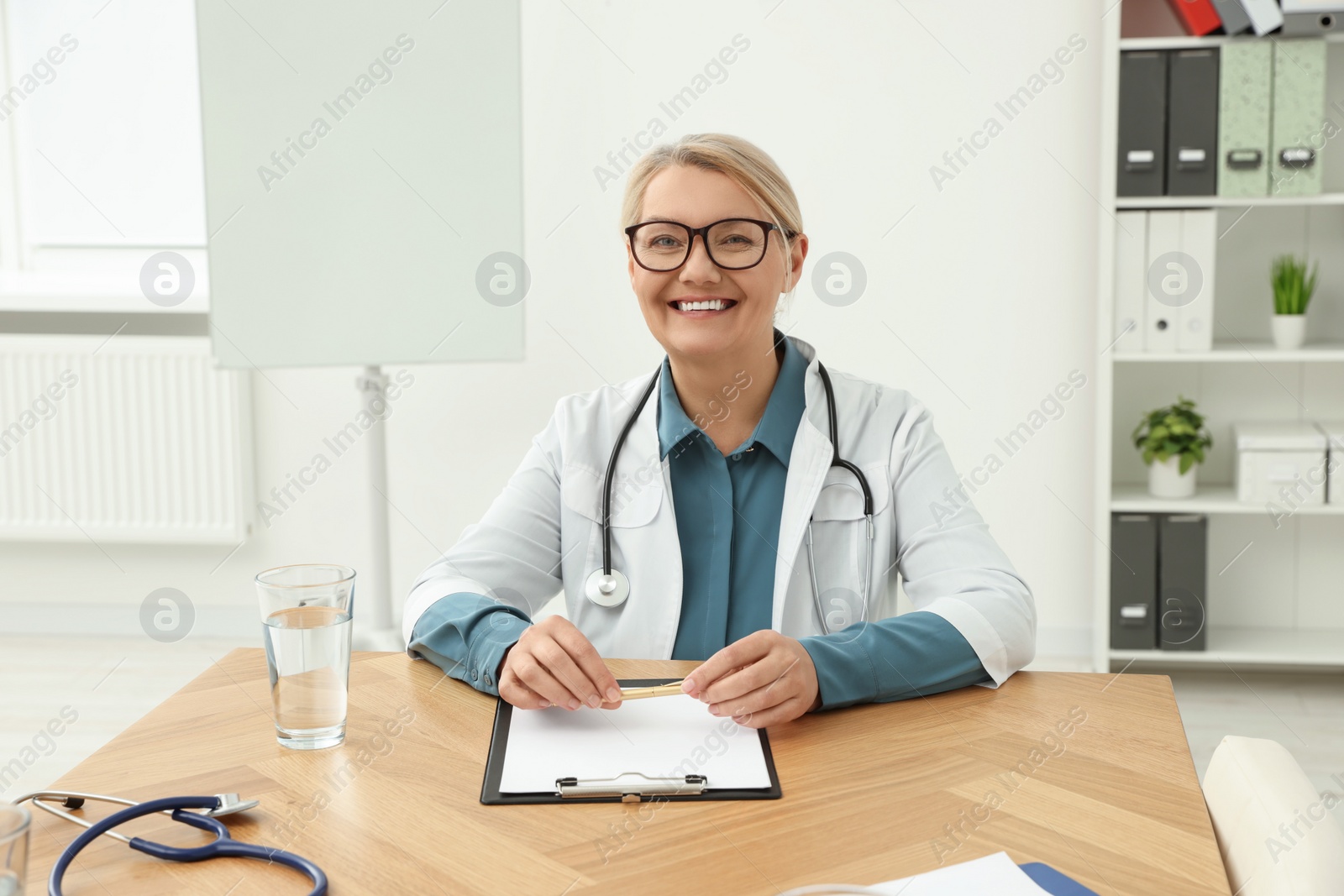 Photo of Professional doctor sitting at wooden table in clinic