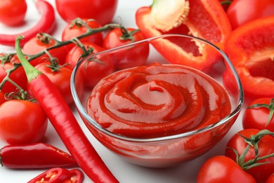 Bowl of tasty ketchup, tomatoes and peppers on white table, closeup