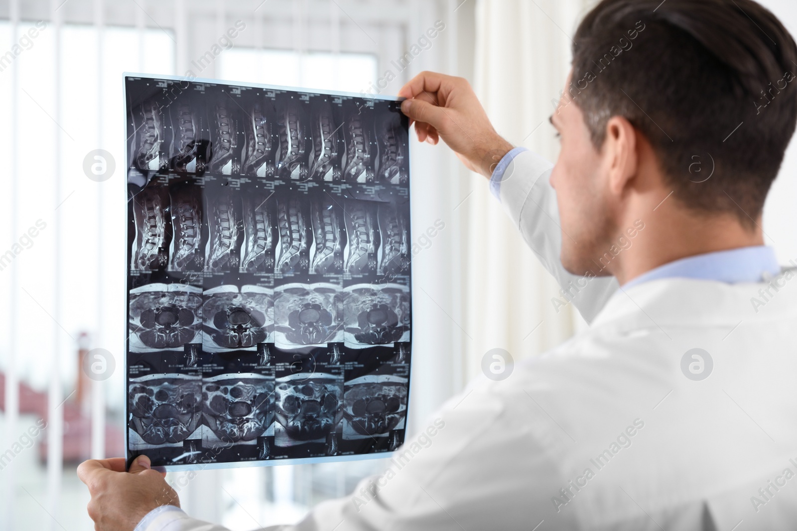 Photo of Orthopedist examining X-ray picture near window in office