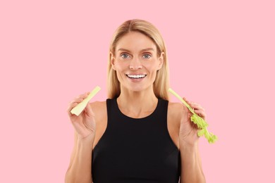 Photo of Woman with pieces of fresh celery stem on pink background