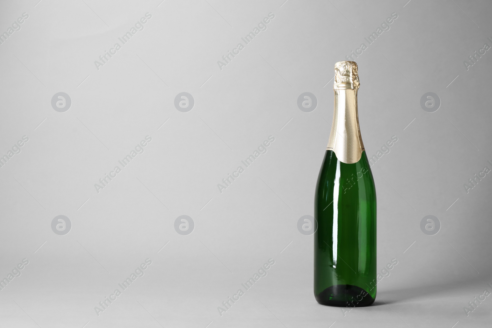 Photo of Bottle of champagne on grey background. Space for text