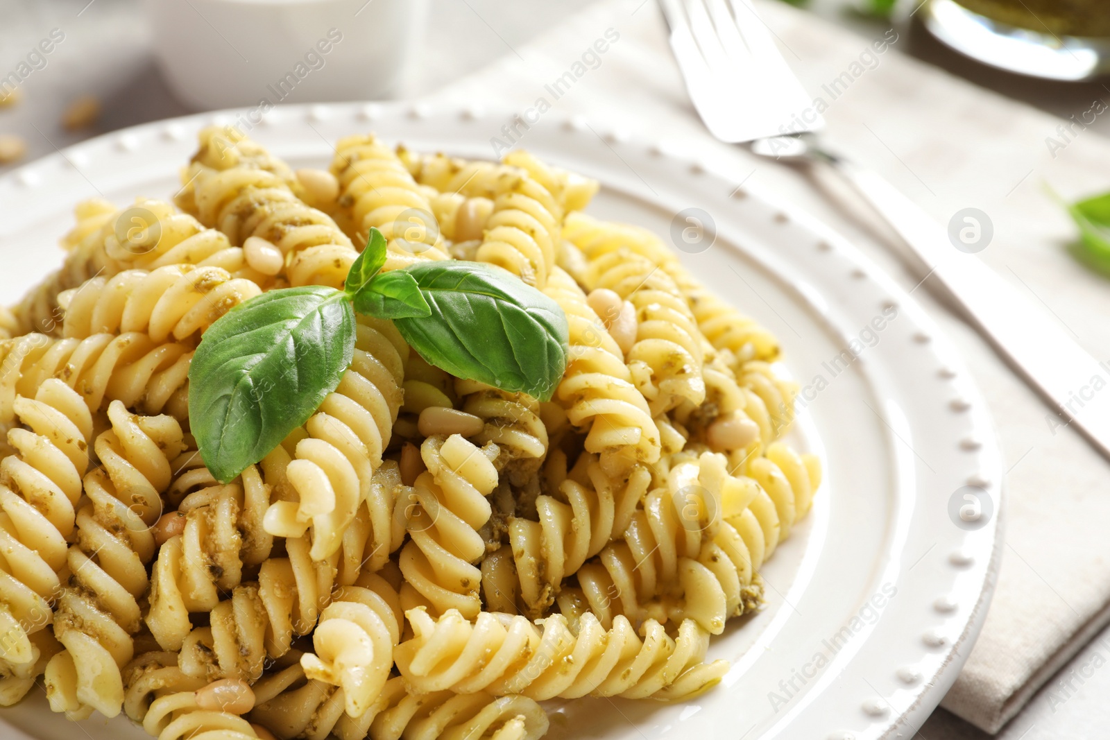 Photo of Plate with delicious basil pesto pasta on table, closeup
